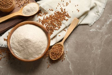 Gri mermer masa üzerinde bir kase karabuğday unu ve tahıl içeren düz bir kompozisyon. Metin için boşluk