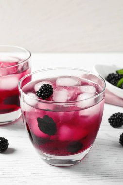 Beyaz ahşap masada lezzetli, ferahlatıcı böğürtlen limonatası.