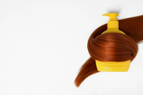 Botella de champú envuelto en mechón de pelo aislado en blanco, vista superior. Productos cosméticos naturales — Foto de Stock