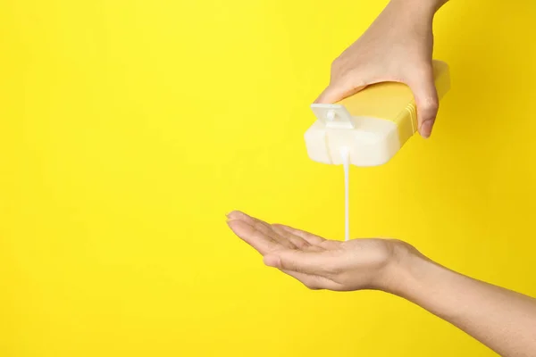 Mulher derramando cabelo produto cosmético na mão sobre fundo amarelo, close-up. Espaço para texto — Fotografia de Stock