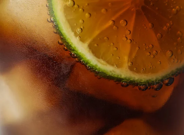 Szklanka orzeźwiającego napoju sodowego z kostkami lodu i limonką, zbliżenie — Zdjęcie stockowe