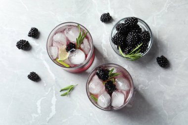 Aydınlık masada böğürtlenli limonata bardaklarıyla yassı kompozisyon