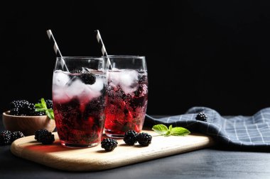 Masanın üzerinde koyu arkaplanda lezzetli, ferahlatıcı böğürtlen limonatası. Metin için boşluk