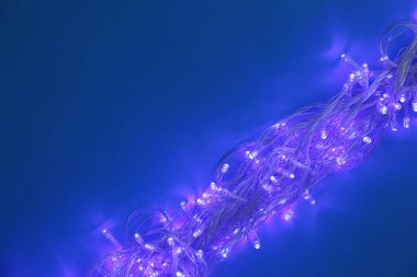 Koyu mavi arka planda parlayan Noel ışıkları, üst görünüm. Metin için alan