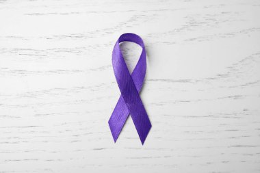 Beyaz ahşap arka plan üzerinde mor kurdele, üst görünüm. Aile içi şiddet bilinci