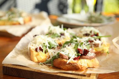 Delicious bruschettas with beef and cheese on table