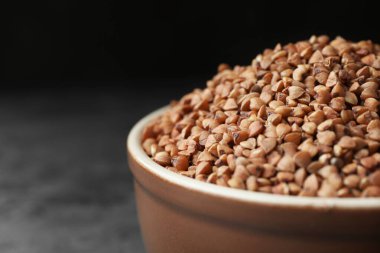 Uncooked buckwheat grains on grey table, closeup