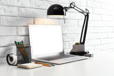 Laptop ve lambalı modern işyeri tuğla duvarın yanında. Tasarım için boşluk