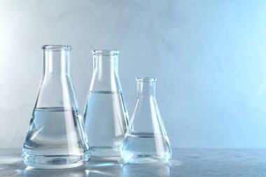 Üzerinde analiz için sıvı örnekleri bulunan laboratuvar camları, tonlu mavi arkaplan, metin için boşluk