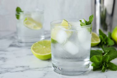 Beyaz mermer masada votka, buz ve limonlu kokteyl.