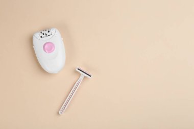 Bej arka planda modern epilator ve ustura, düz yatıyordu. Metin için boşluk
