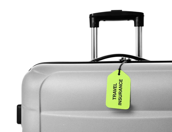 Grå resväska med reseförsäkring etikett på vit bakgrund, närbild — Stockfoto