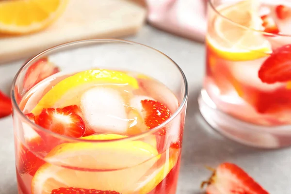Вкусный освежающий напиток с клубникой и лимоном на светло-сером столе, крупным планом — стоковое фото