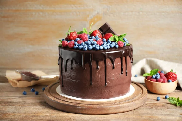 Freshly made delicious chocolate cake decorated with berries on wooden table — Stock Photo, Image