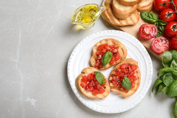 Composizione stesa piatta di gustose bruschette con pomodori sul tavolo in marmo grigio chiaro, spazio per il testo — Foto Stock