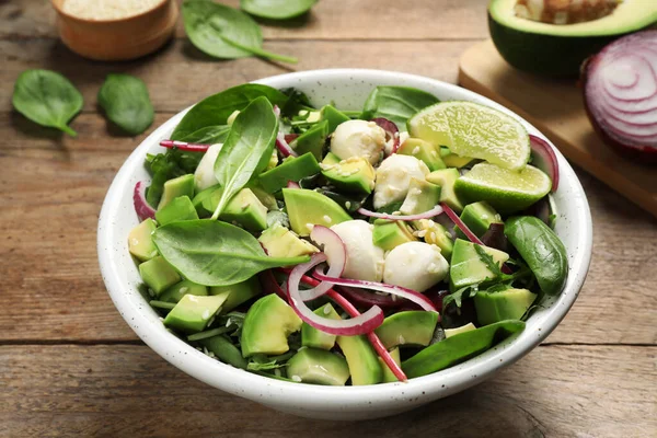 Köstlicher Avocadosalat mit Mozzarella auf Holztisch — Stockfoto