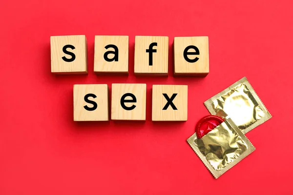 Ord Safe Sex gjorda med träkuber och glänsande kondomer på röd bakgrund, platt låg — Stockfoto
