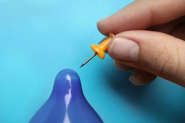 Donna piercing preservativo gonfiato con perno su sfondo azzurro, primo piano. Sesso sicuro — Foto Stock