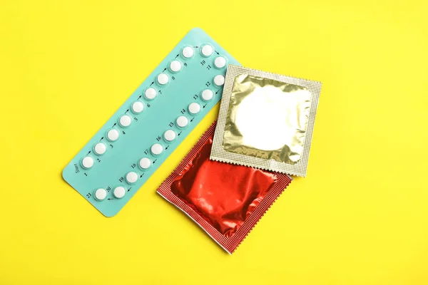 Préservatifs et pilules contraceptives sur fond jaune, à plat. Concept de sexe sûr — Photo