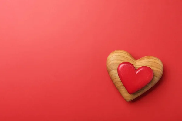 Corazones de madera sobre fondo rojo, vista superior. Espacio para texto — Foto de Stock