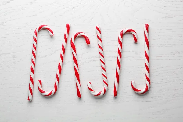 Candy canes on white wooden background, flat lay. Traditional Christmas treat