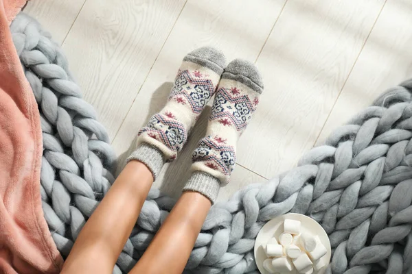 Woman wearing knitted socks on wooden floor, top view. Warm clothes — Stock Photo, Image