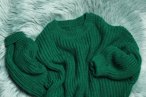 Μαλακό πλεκτό πουλόβερ σε πράσινο γούνινο χαλί, επίπεδο lay — Φωτογραφία Αρχείου