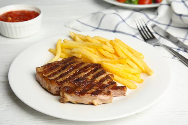 Sabroso filete de res a la parrilla y papas fritas en mesa de madera blanca — Foto de Stock