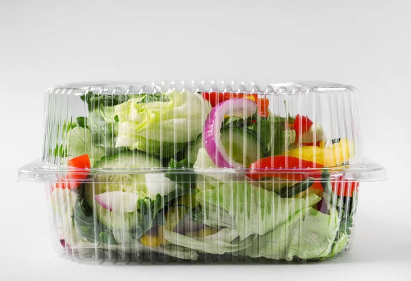 Plastic container with fresh salad on light grey background — Stock Photo, Image