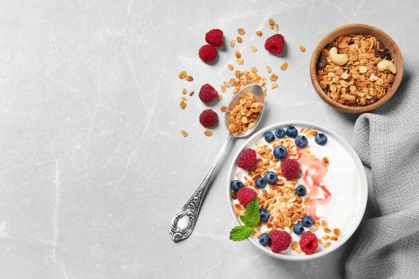 Здорова домашня гранола з йогуртом та ягодами, подається на світло-сірому столі, плоска. Простір для тексту — стокове фото