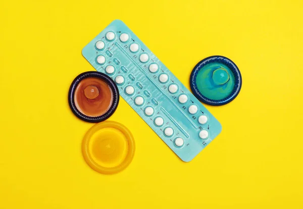 Kondomer och p-piller på gul bakgrund, platt låg. Säkert sex koncept — Stockfoto