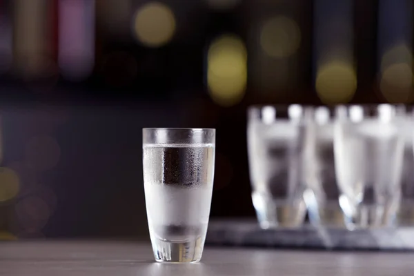 Tiro de vodka na mesa contra fundo desfocado — Fotografia de Stock