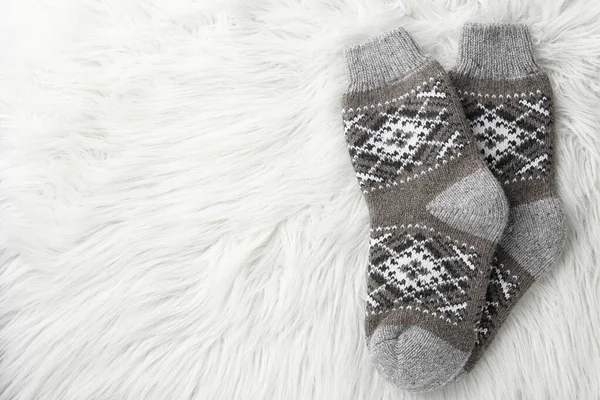 Knitted socks on white faux fur, flat lay. Space for text — Stock Photo, Image