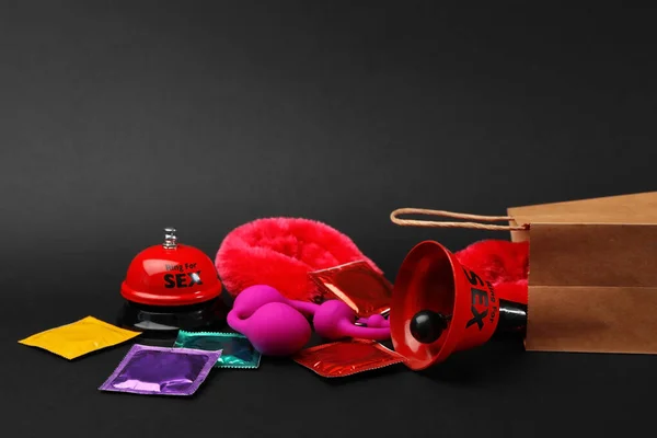 Bolsa de compras y diferentes juguetes sexuales sobre fondo negro — Foto de Stock