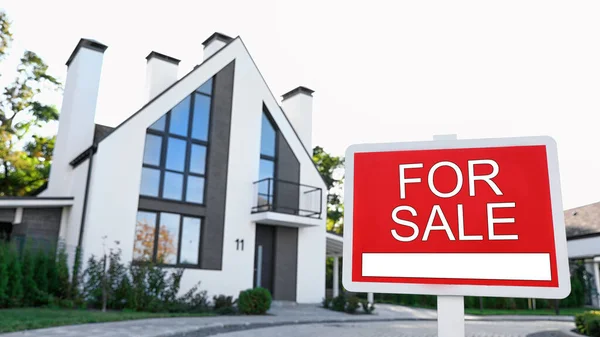 Red real estate sign near house outdoors on sunny day — Stock Photo, Image