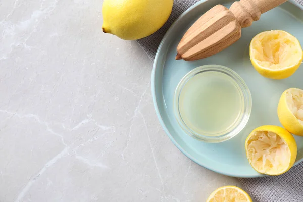 Плоска композиція зі свіжими лимонами, соком та реамером на сірому мармуровому столі. Простір для тексту — стокове фото