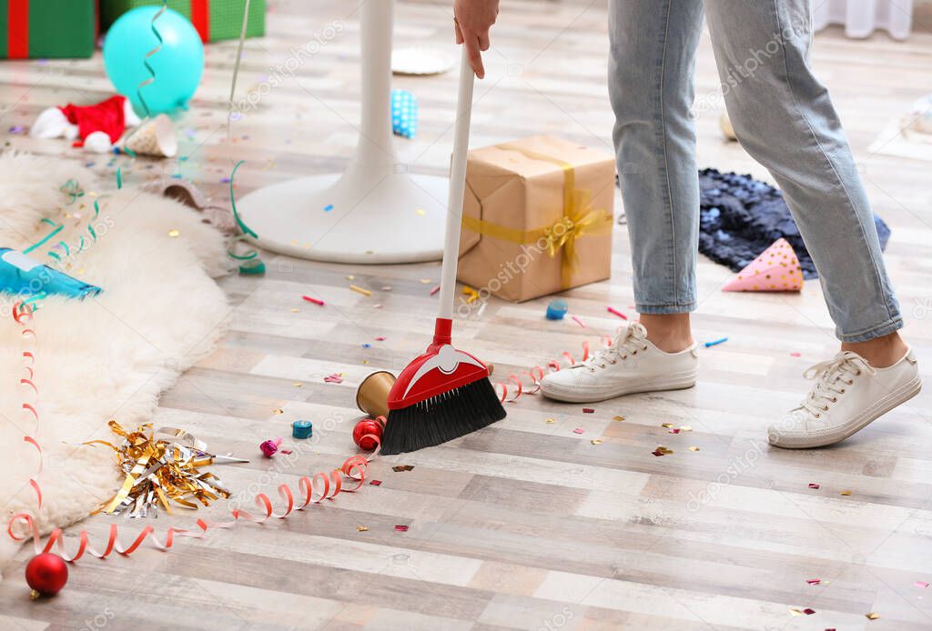 Woman sweeping messy floor after party, closeup