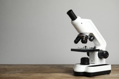 Modern mikroskop ahşap masada gri arka plana karşı, yazı için alan. Tıbbi ekipman