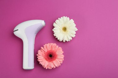 Modern fotoepilatör ve mor arka planda çiçekler, düz yatıyordu.