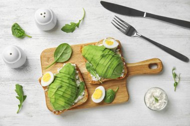 Flat lay composition with avocado toasts on white wooden table