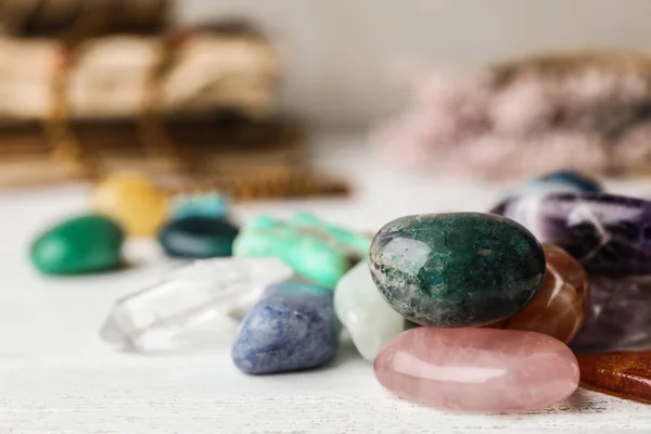 Montón de diferentes piedras preciosas sobre mesa de madera blanca. Espacio para texto — Foto de Stock