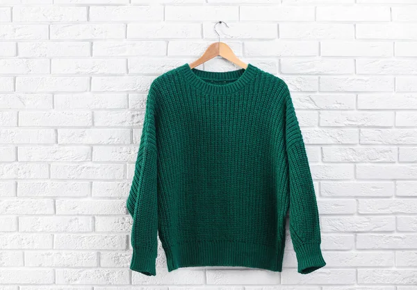 Kleiderbügel mit stylischem Pullover an Ziegelwand — Stockfoto