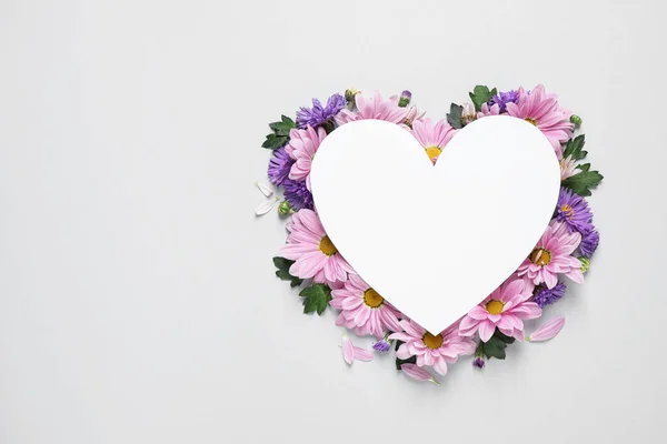 Hermosas flores de manzanilla y tarjeta de papel en forma de corazón sobre fondo blanco, vista superior con espacio para texto — Foto de Stock