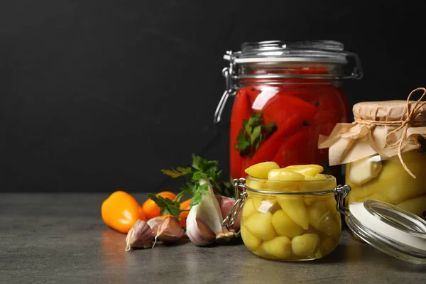 Glas krukker med syltede peberfrugter på grå bord. Plads til tekst - Stock-foto