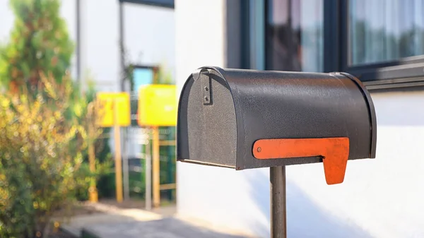 Cassetta postale nera vicino casa all'aperto nella giornata di sole — Foto Stock