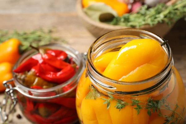 Glass jars with pickled peppers on table, closeup — Stock fotografie