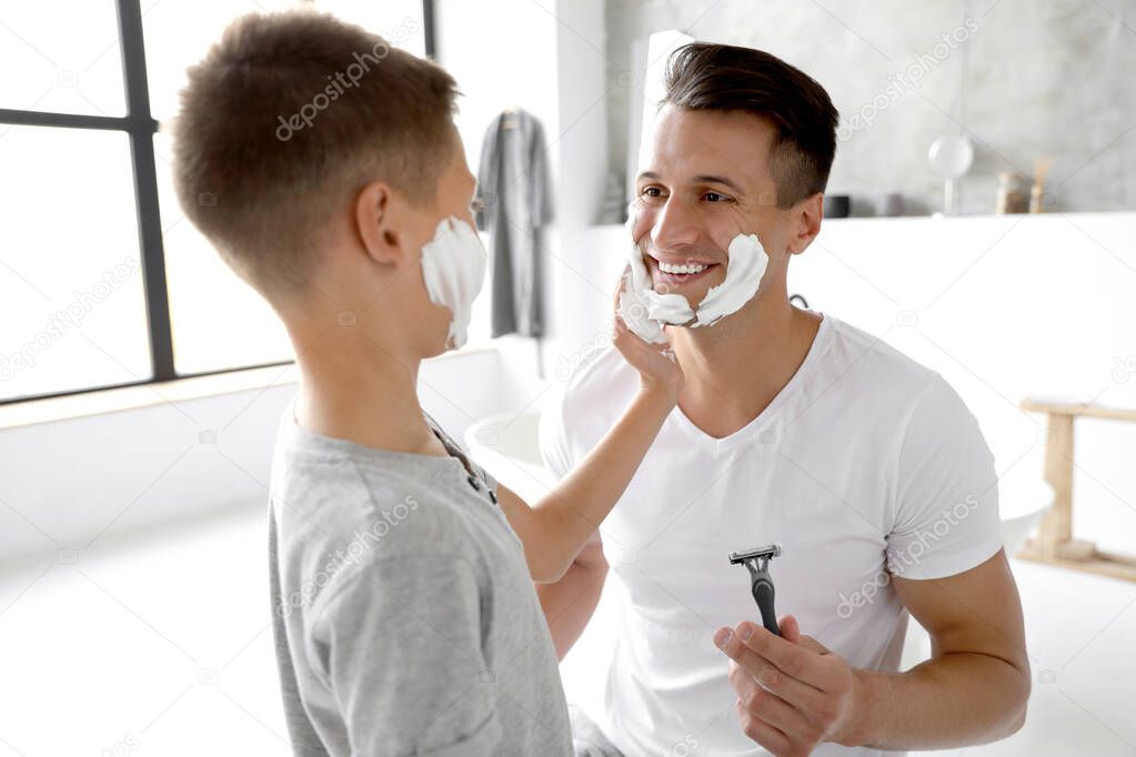 Son applying shaving foam onto father's face in bathroom