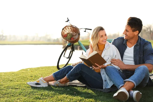 快乐的年轻夫妇在户外野餐的时候看书 — 图库照片
