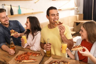 Bir grup arkadaş kafede lezzetli pizzalarla eğleniyorlar.