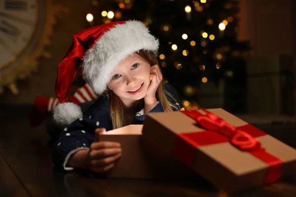 Cute child opening magic gift box near Christmas tree at night — ストック写真
